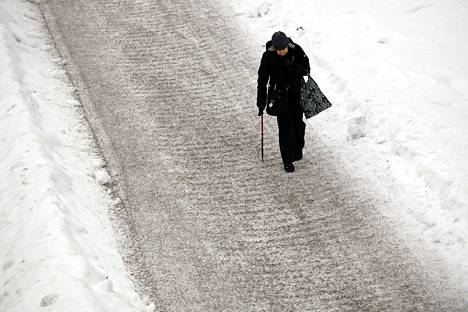 Jalankulkijoita on varoitettu jäätävän sateen aiheuttamasta erittäin liukkaasta säästä eteläisessä Suomessa. Jalankulkija huolella hiekoitetulla jalkakäytävällä Espoossa maanantaina.
