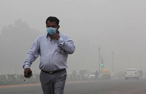 Mies suojaa itseään ilmansaasteilta Delhissä sunnuntaiaamuna 3. marraskuuta.