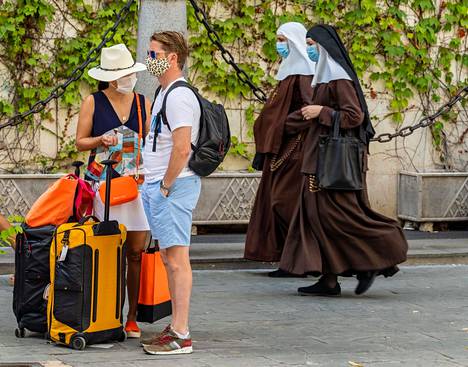 Turistit odottivat bussia nunnien kävellessä Sevillan keskustassa 3. elokuuta. Espanjassa aluekohtaiset erot koronatartunnoissa ovat nyt erityisen suuria.