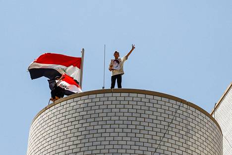 Mielenosoittaja seisoi lauantaina Irakin parlamenttirakennuksen päällä pidellen Muqtada al-Sadrin kuvaa.