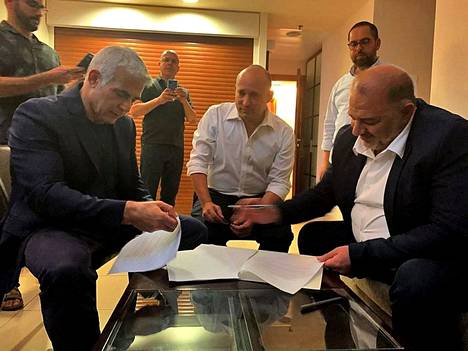 Hallitusneuvottelija Jair Lapid (vas.), tuleva pääministeri Naftali Bennett ja palestiinalaisten islamistisen puolueen Ra’amin johtaja Mansur Abbas allekirjoittivat sopimuksen hallituksen muodostamisesta torstaina. 