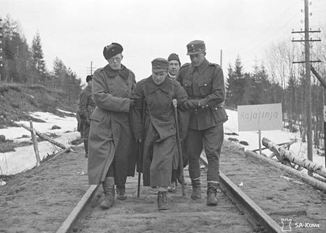 Suomalaisten ja neuvostoliittolaisten vankien vaihtoa tehtiin Vainikkalassa talvisodan päätyttyä huhtikuussa 1940. Toisen jalkansa menettänyt vapautettu suomalainen autetaan rajalinjan yli.