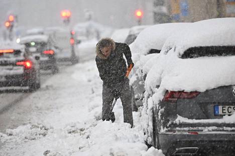 Autoilija kaivoi autoaan lumen alta Tukholmassa maanantaina.