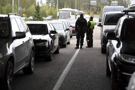 Suomalaiset rajavartijat seisoivat venäläisten autojen välissä Vaalimaalla sunnuntaina.