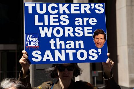 Mielenosoittaja piteli kylttiä, jossa syytettiin Tucker Carlsonia valehtelusta, Fox Newsin toimituksen ulkopuolella New Yorkissa 11. huhtikuuta.
