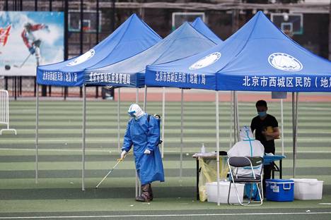 Suojavarusteisiin pukeutunut työntekijä puhdisti stadionia Pekingissä Kiinassa maanantaina. Viranomaiset tekevät stadionilla koronavirustestejä.