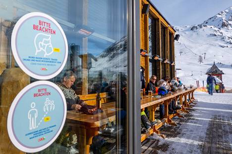 Obertauernin hiihtokeskuksessa ihmiset nauttivat juomia ulkoterassilla tammikuun puolivälissä. Itävallan hiihtokeskuksiin pääsee vain rokotuspassilla.