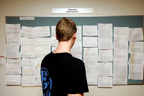 Nuori mies tutki ilmoitustaulua työnhakukeskuksessa Helsingissä.