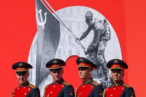 Venäläissotilaita Moskovan Punaisella torilla lauantaina. Taustalla olevan jättijulisteen kuvassa puna-armeijan sotilas nostaa Neuvostoliiton lippua Berliinin valtiopäivätalon ylle toukokuun alussa 1945.
