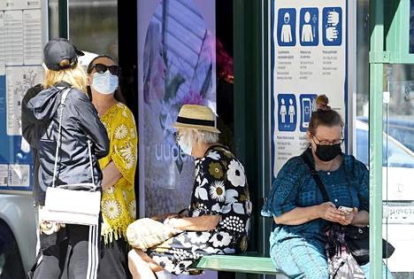 Syksyn mahdollisissa koronatoimissa on vielä paljon epävarmuuksia. Heinäkuussa maskia käyttävät ihmiset odottivat raitiovaunua pysäkillä Helsingissä. 
