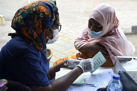 Terveydenhuollon työntekijä keskusteli Astra Zenecan koronarokotteen saaneen naisen kanssa rokotuksen jälkeen Nigerian Lagosissa marraskuussa.