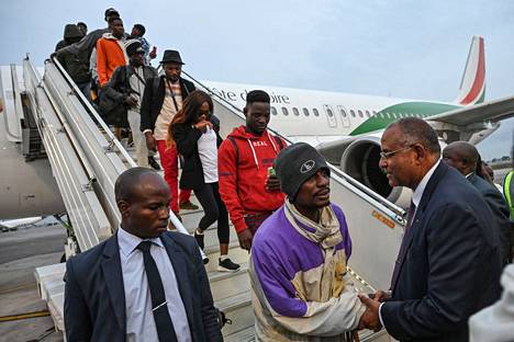 Norsunluurannikon pääministeri Patrick Achi (oike.) toivotti Tunisiasta paluulennolla kotiutettuja ihmisiä Abidjanin kaupungissa lauantaina.