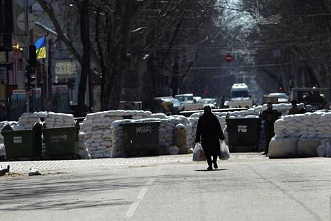 Nainen kantoi muovikasseja kohti tiesulkua Odessassa 17. maaliskuuta.