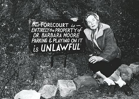 Englantilainen maratonkävelijä ja kasvissyöjä, tri Barbara Moore, tuomittiin hiljakkoin vankeuteen, koska hän kielsi naapureiltaan käyttöoikeuden talonsa pihamaahan. Sisupussi ei kuitenkaan lannistunut, vaan ryhtyi nälkälakkoon, minkä seurauksena hänet vapautettiin. Kuvassa Barbara pihamaalleen pystyttämänsä julisteen vieressä, jossa lukee &#34;Tämä piha on kokonaan tri Barbara Mooren omaisuutta. Pysäköiminen tai leikkiminen sillä on laitonta.&#34;