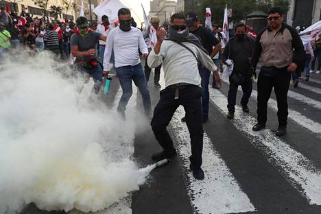 Mielenosoittajat yrittivät suojautua kyynelkaasulta Limassa lauantaina.