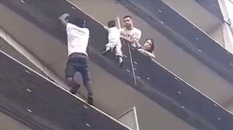 22-vuotias maahanmuuttaja kiipesi pelastamaan kerrostalon parvekkeen kaiteesta riippuneen pikkulapsen Pariisissa – suora lähetys tapaamisesta Macronin kanssa noin kello 10.50