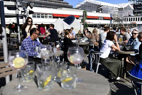 Ihmisiä nauttimassa aurinkoisesta säästä Lasipalatsinaukion terassilla Helsingissä 22. toukokuuta.