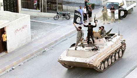 Ääri-islamistisen Isis-järjestön taistelijat sotilasparaatissa Raqqan provinssissa Syyriassa 30. kesäkuuta 2014 päivätyssä kuvassa.