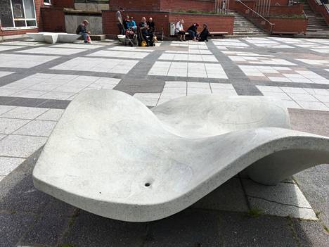 Vuonna 2020 aallon malliset penkit koristivat vielä Koivutorin aukiota. Taustalla ihmiset istuvat Flor Grande  ja Flor Pequeña -nimisten betoni-istuimien päällä. 