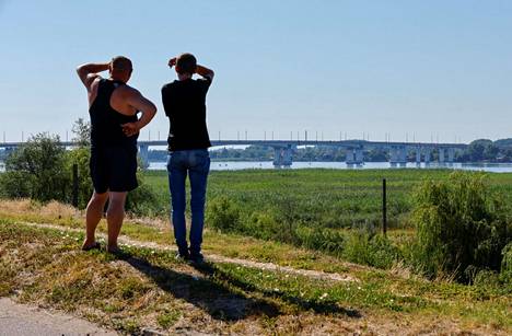 Мужчины смотрят в сторону Антоновского моста. 27 июля 2022 года. Фото: Александр Ермошенко / Reuters