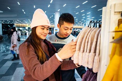 Moon Sze (vas.) ja Ryan Leung tutkivat vaatteita Helsinki-Vantaan Muumi-tuotteita myyyvässä kaupassa ennen lentoaan kotiin Hongkongiin.
