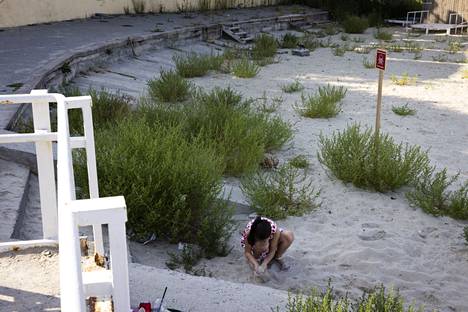 Девочка играет в песке рядом со знаком “Осторожно, мины”. Фото: Юхани Нииранен / HS
