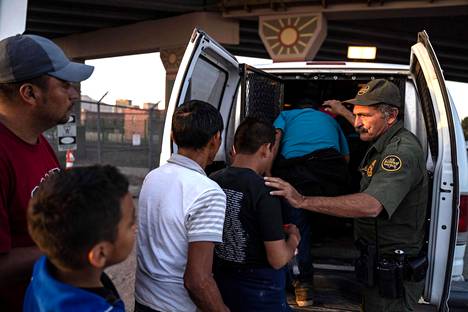 Yhdysvaltain maahanmuuttoviranomainen ohjasi toukokuussa Texasissa siirtolaisia autoon, joka kuljettaa heidät siirtolaisten pidätyskeskukseen.
