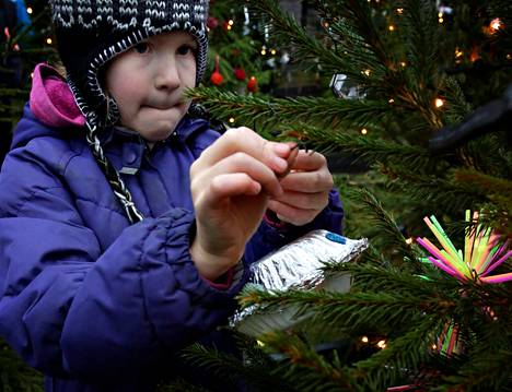 Laura Tirkkonen Vartiokylän ala-asteelta ripusti itse tekemänsä lentävän lautasen Kansallismuseon joulukuusimetsään perjantaina.