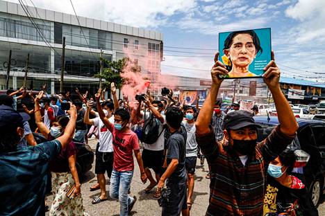 Mielenosoittajat marssivat Aung San Suu Kyin kuvien kanssa lauantaina Yangonissa.