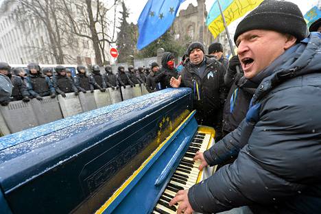 Mielenosoittaja soittaa pianoa poliisirivistön edessä Kiovassa lauantaina.