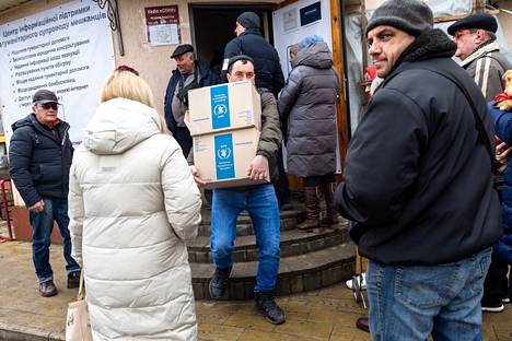 Dmitri Didenko kantaa kahta ruokapakettia kotiin avustuspisteeltä. 