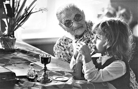 Aina-täti ja pastorin pikku Katja; ehtoolliskalkki ja virvoitusjuomapullo samassa pöydässä.