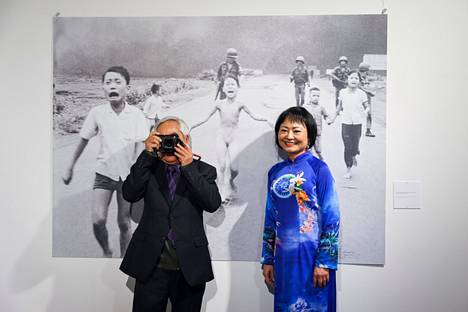 Nick Ut ja Phan Thi Kim Phuc toukokuussa Milanossa pidetyssä näyttelyssä takanaan  ikoninen valokuva Vietnamin sodasta. 