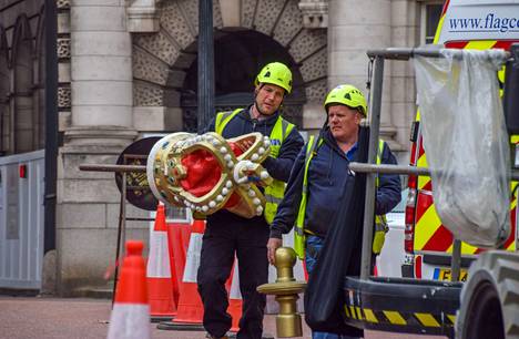 Kypäräpäinen työmies kantaa kruunukoristetta kruunajaisia varten Lontoossa.