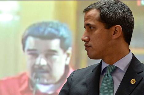 Juan Guaidó kuvattuna vuonna 2019 taustallaan kuva Nicolás Madurosta.