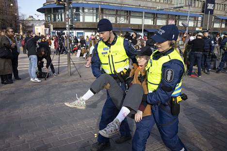 Poliisit kantoivat mielenosoittajaa pois Mannerheimintieltä perjantai-iltana.