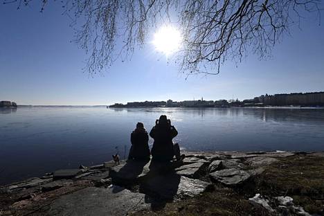 Pariskunta ja koira nauttivat auringosta Tervasaaren rannassa Helsingissä lauantaina 12. maaliskuuta 2022.