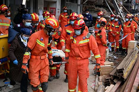 Pelastustyöntekijät kuljettavat kerrostalon romahduksessa loukkaantunutta henkilöä pois onnettomuuspaikalta Keski-Kiinan Changshassa viime sunnuntaina.