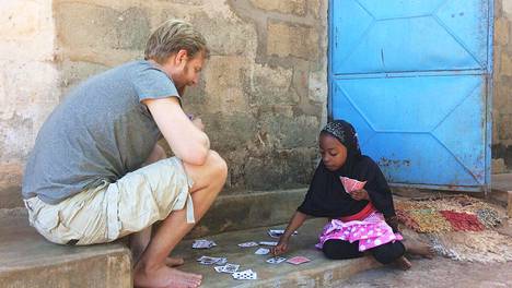 Brian pelaa korttia pikkutytön kanssa Sansibarilla.