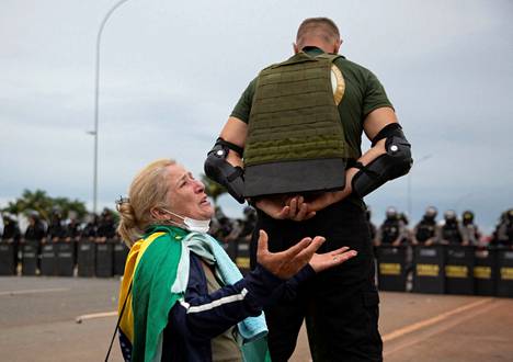 Bolsonaron kannattaja suojasi toista, rukoilevaa kannattajaa mielenosoituksessa Brasíliassa sunnuntaina.