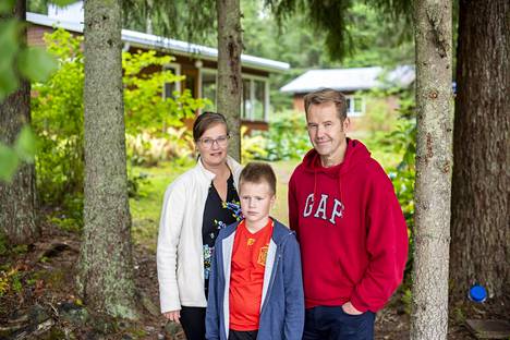 Merja Olari-Sintonen ja Petri Sintonen sekä Leevi-poika vuokralle laitetun mökkinsä pihalla.
