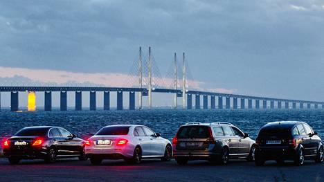 Pariskunnat istuivat autoissa ja katsoivat Juutinrauman siltaa auringon laskiessa Malmössä.