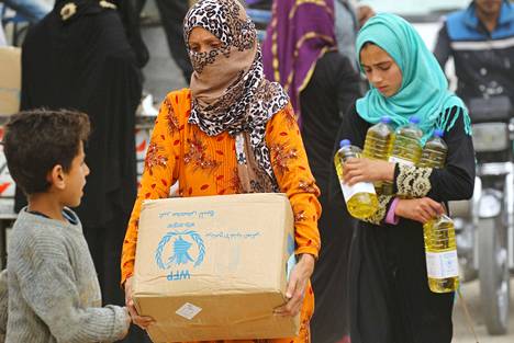 Syyrialaiset pakolaisnaiset kantoivat ruoka-apupaketteja Syyrian Raqqassa vuonna 2018.