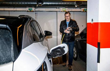 Pasi Lehtinen kytkee taloyhtiön pysäköintihallissa sähköautonsa lataukseen.