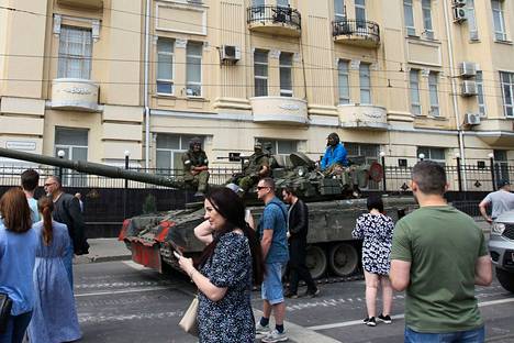 People around an armored vehicle parked on the street.