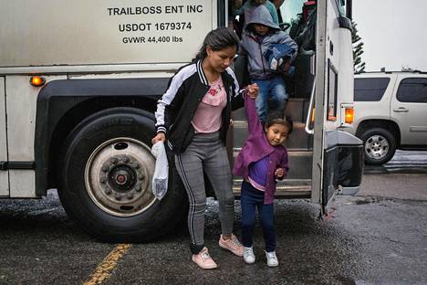 Keskiamerikkalaisia turvapaikanhakijoita nousi bussista, kun heitä siirrettiin viranomaisten huomasta hyväntekeväisyysjärjestön suojataloon.