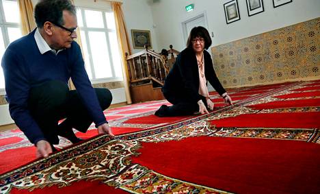 Fazile ja Samil Nasretdin levittävät rukousmattoja moskeijan rukoushuoneen lattialle.