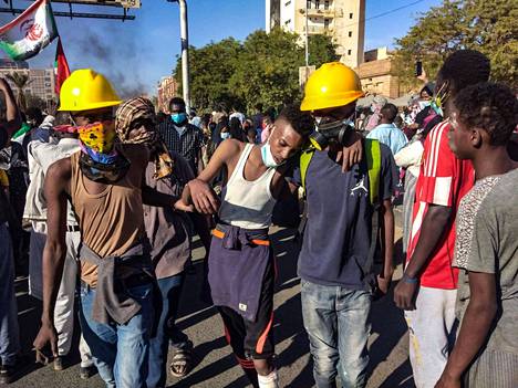 Nuoret miehet auttoivat mielenosituksessa loukkaantunutta toveriaan Sudanin pääkaupungissa Khartumissa 30. joulukuuta 2021.