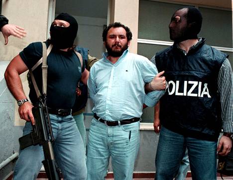 Arkistokuva vuodelta 1996 Giovanni Bruscasta, jota kasvonsa peittäneet poliisit saattavat vankilaan.