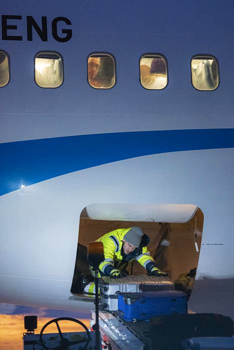 Lentomatkailija seuraa, kun Enontekiön lentokentälle saapuneen koneen ruumaa tyhjennetään matkalaukuista.